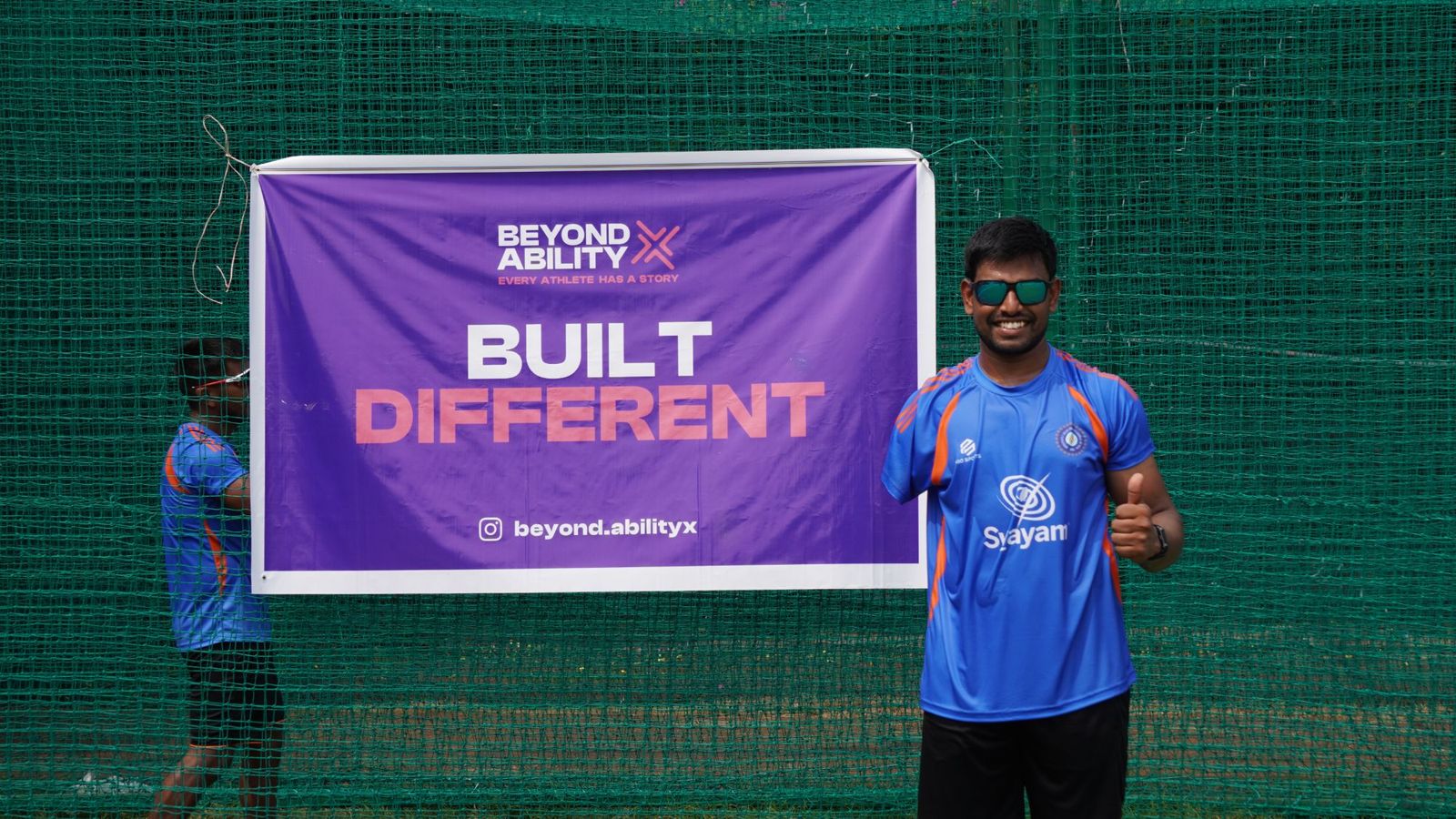 A BAX athlete giving a thumbs up in front of a Beyond Ability X banner